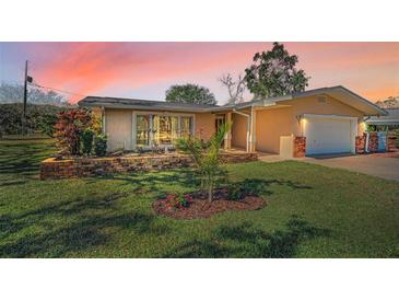 Charming home with a well-maintained lawn and brick garden bed, highlighted by a picturesque sunset sky at 4191 39Th S St, St Petersburg, FL 33711