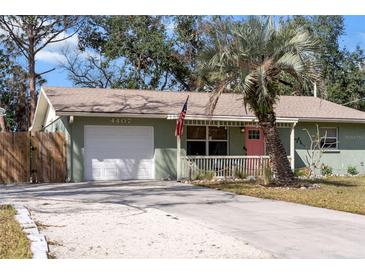 Charming single-story home featuring a light green exterior, well-manicured lawn and a bright pink front door at 4407 Parnell Dr, Sarasota, FL 34232