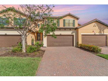 Charming two-story townhome with a brown garage door and a brick driveway at 10800 Tarflower Dr # 202, Venice, FL 34293