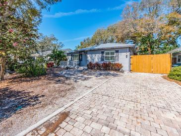 Charming single-story home featuring a manicured lawn, brick driveway, and light gray exterior paint at 1108 Commodore St, Clearwater, FL 33755