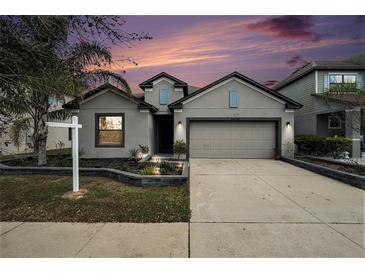 Charming single-Gathering home with a well-manicured lawn and a two-car garage at sunset at 14330 Fissore Blvd, Wimauma, FL 33598
