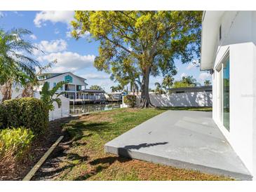 Inviting backyard space with a concrete patio, lush greenery, and waterfront access via a private dock at 8704 Thornwood Ln, Tampa, FL 33615