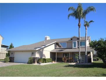 Charming two-story home with manicured lawn, mature palm trees, and an attached two-car garage at 130 Water Oak Way, Oldsmar, FL 34677