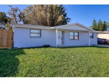 Charming single-story home with stucco exterior, a well-maintained yard, and beautiful front door at 7234 Castanea Dr, Port Richey, FL 34668