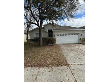 Inviting single-Gathering home featuring a two-car garage and mature landscaping at 8480 Southern Charm Cir, Brooksville, FL 34613