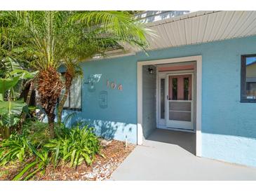 Inviting front entrance with a decorative palm tree and number plate on a bright blue building exterior at 104 Anclote Rd, Tarpon Springs, FL 34689