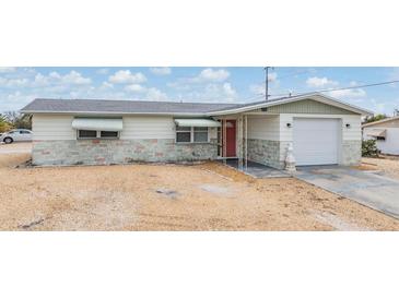 Classic home featuring a red front door, one car garage, and minimalist landscaping at 1118 Excalibur St, Holiday, FL 34690