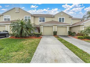 Two-story townhome featuring a two-car garage, well-kept landscaping, and a concrete driveway at 11266 Kapok Grand Cir, Madeira Beach, FL 33708