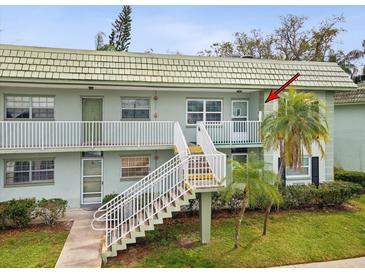 Two-story condo building with white railings, staircase and tropical landscaping at 1433 S Belcher Rd # F20, Clearwater, FL 33764