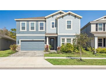 Charming two-story home showcasing a welcoming blue exterior, manicured lawn, and an attached two-car garage at 17953 Ramble On Way, Land O Lakes, FL 34638