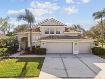 Charming two-story home boasts a spacious three-car garage, tile roof, and well-manicured landscaping with palms at 18014 Forest Retreat Ln, Tampa, FL 33647