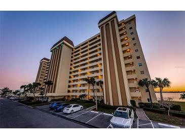 Multi-story tan condo building featuring numerous balconies and meticulous landscaping at 4525 Cove Cir # 705, St Petersburg, FL 33708