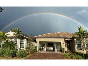 Charming home with a tile roof, lush landscaping, and a vibrant rainbow in the background at 13100 Rinella St, Venice, FL 34293