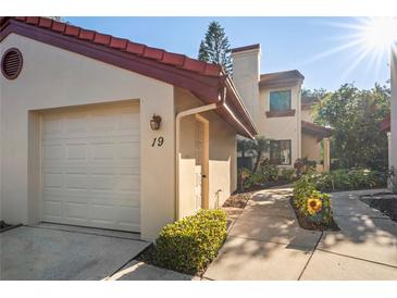 Charming condo featuring a one-car garage, red tile roof and well-manicured landscaping at 3460 Countryside Blvd # 19, Clearwater, FL 33761