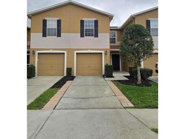 Inviting townhouse featuring a well-maintained lawn, two-car garage, and neutral exterior color scheme at 4224 Winding River Way, Land O Lakes, FL 34639