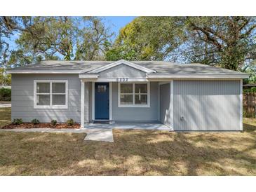 Charming single-story home with a fresh gray exterior, blue front door and well-maintained yard at 6802 N 15Th St, Tampa, FL 33610