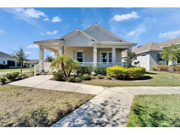 Charming single-story home with a welcoming front porch, lush landscaping, and a well-manicured lawn at 729 Winterside Dr, Apollo Beach, FL 33572
