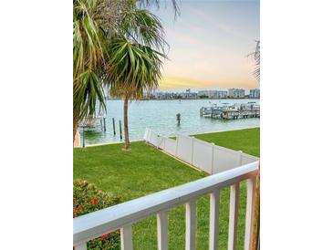 Beautiful waterfront view featuring palm trees, green grass, and condos in the distance at 8901 Blind Pass Rd # 224, St Pete Beach, FL 33706