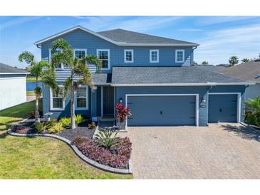 Charming two-story home boasts a lush landscaped yard, a three-car garage and a paver driveway at 11305 Emerald Shore Dr, Riverview, FL 33579