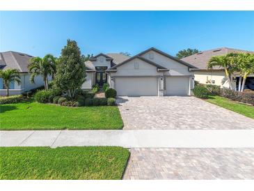 Charming home featuring a three-car garage, brick driveway, well-maintained landscaping, and lush green lawn at 12296 Keyridge Loop, Largo, FL 33778