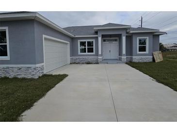 Charming home featuring a two-car garage, gray stucco exterior, and a concrete driveway at 14300 Kay Ln, Port Charlotte, FL 33981