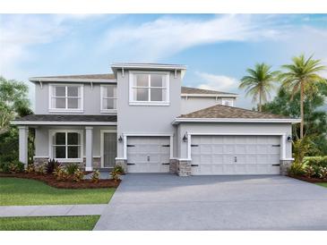 Two story home featuring a gray exterior, a two car garage, a manicured lawn, and tasteful landscaping at 3422 Hazel Hollow Way, Plant City, FL 33565