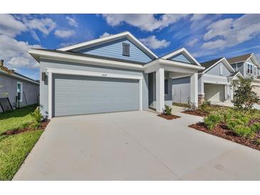 Charming one-story home featuring a two-car garage and inviting front porch with manicured landscaping at 6042 Golden Nettle Dr, Apollo Beach, FL 33572