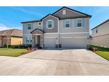 Two story home with a two car garage, light gray paint, stone entryway and shutters on the windows at 8816 Mugnai St, Riverview, FL 33578