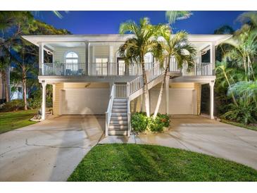 Two-story home with a double garage, white stairs, and a charming front balcony with palm trees at 1051 Point Seaside, Crystal Beach, FL 34681
