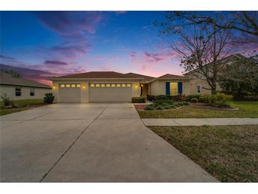 Inviting home with a three-car garage and a well-manicured lawn at dusk at 5325 Sandy Shell Dr, Apollo Beach, FL 33572