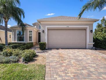 Charming one-story home with a two-car garage, lush landscaping, and brick driveway at 1703 Pacific Dunes Dr, Sun City Center, FL 33573