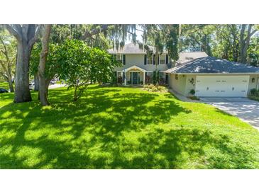 Beautiful two-story home featuring a lush front yard with mature trees and attached two-car garage at 1857 Castle Woods Dr, Clearwater, FL 33759