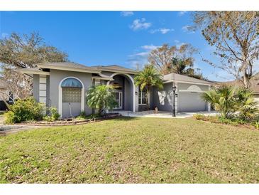 Charming single-story home with a well-manicured lawn, landscaped garden, and a gray exterior at 2823 Clubhouse Dr, Plant City, FL 33566
