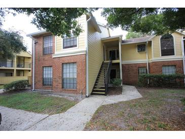 Two-story condo featuring brick and siding exterior with covered entry and a stairway to the second floor at 8728 Mallard Reserve Dr # 102, Tampa, FL 33614