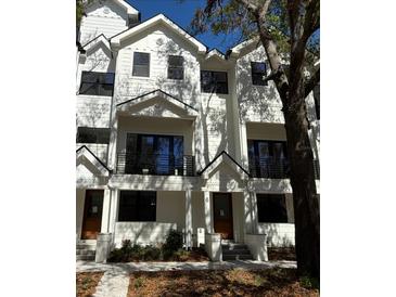 Beautiful townhome with a modern white exterior, black trim and railing details, and a well-kept yard at 1801 N Morgan St # 6, Tampa, FL 33602