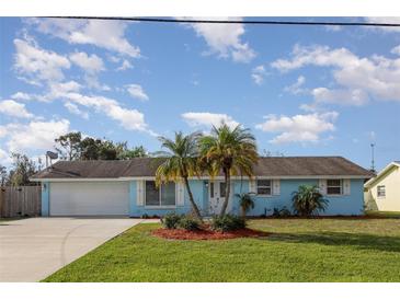 Charming single-story home features a blue exterior, well-manicured lawn, and beautiful palm trees in front at 608 Florida S Cir, Apollo Beach, FL 33572