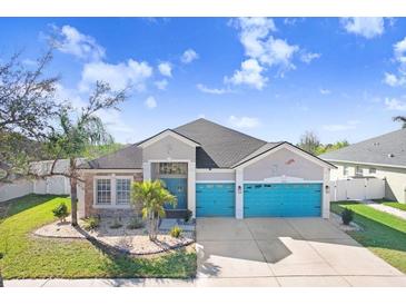 Charming single-Gathering home featuring a three-car garage and eye-catching turquoise doors at 13235 Graham Yarden Dr, Riverview, FL 33579