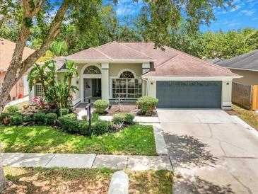 Charming one-story home with lush green lawn, mature trees, and a well-manicured front yard at 3616 Cypress Meadows Rd, Tampa, FL 33624