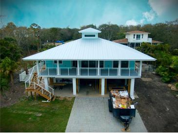 Unique waterfront home featuring elevated construction and a large metal roof at 406 Shore W Dr, Oldsmar, FL 34677