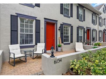 Charming townhome with a bright red door, black shutters, and a cozy front porch sitting area at 6134 Fishhawk Crossing Blvd, Lithia, FL 33547