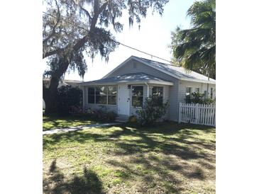 Charming home featuring a picket fence, manicured lawn, and mature trees adding curb appeal and shade at 4905 Court St, Zephyrhills, FL 33541