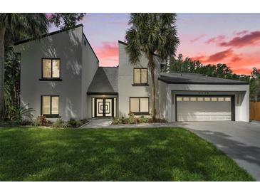 Contemporary two-story home with a well-manicured lawn, palm trees and modern architectural design at 4520 Pine Hollow Dr, Tampa, FL 33624
