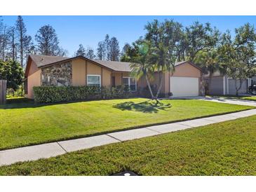 Charming single-Gathering home features a stone accent wall, mature landscaping, and a well-manicured lawn at 4908 Oakshire Dr, Tampa, FL 33625