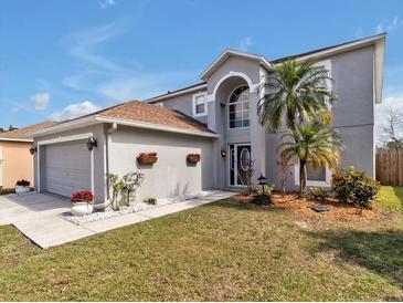 Charming two-story home with a well-manicured lawn, complemented by palm trees and flower boxes at 5337 Treig Ln, Wesley Chapel, FL 33545