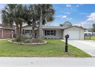 Charming single-story home featuring a well-maintained lawn, mature palms, and an attached one-car garage at 5440 Quist Dr, Port Richey, FL 34668