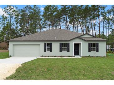 Charming single-story home features a well-maintained lawn, neutral paint, a two-car garage, and classic black shutters at 12341 Filbert Rd, Weeki Wachee, FL 34614