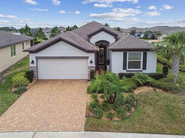 Charming single-story home with a brick driveway, manicured lawn, and decorative stone accents at 19477 Coastal Shore Ter, Land O Lakes, FL 34638