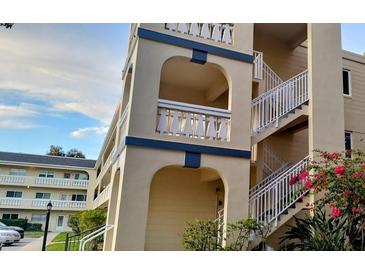 Three story building with balconies with archways, a staircase and pink flowers at 2256 Spanish Dr # 42, Clearwater, FL 33763