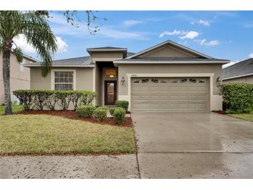 Charming single-story home with a two-car garage, lush landscaping, and a well-maintained lawn at 13454 Graham Yarden Dr, Riverview, FL 33579