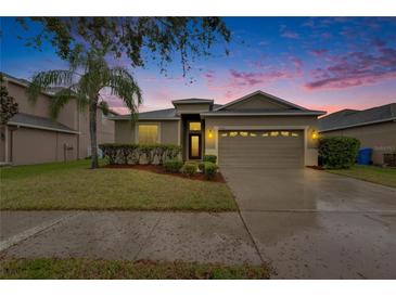 Charming home with a two-car garage and landscaped front yard highlighted by a beautiful sunset at 13454 Graham Yarden Dr, Riverview, FL 33579